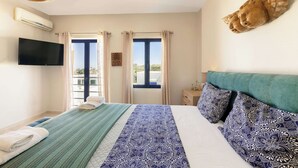 Habitació d'hotel amb llit, televisió de pantalla plana, finestra amb cortines i un àngel decoratiu penjat a la paret.