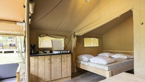 A compact, well-lit tent with a kitchenette, a bed with pillows, and a small seating area. - Terrace Apartment With Forest (Manhay)
