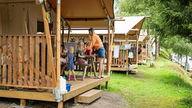 A series of wooden cabins with open porches, connected by a wooden deck. - Terrace Apartment With Forest (Manhay)