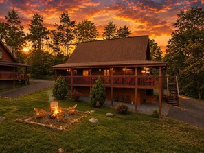A lodge with a covered porch, outdoor seating, and a fire pit.
