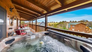 Un jacuzzi en una terraza de madera con vistas a casas y árboles.