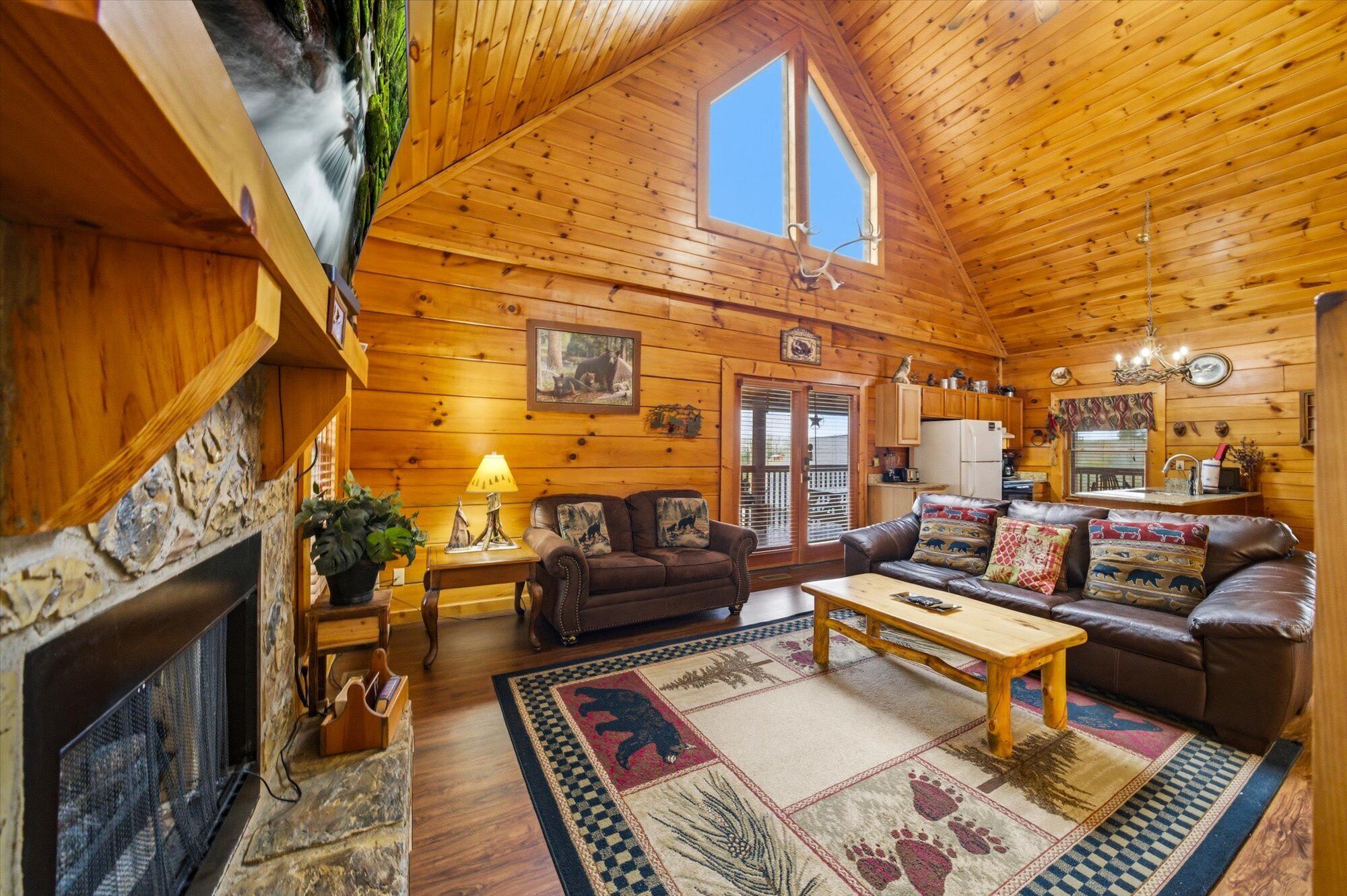 L’intérieur d’un chalet confortable, avec une cheminée, des canapés en cuir, une table à manger et un coin cuisine.