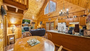 Un acogedor interior de cabaña con comedor, cocina y sala de estar.