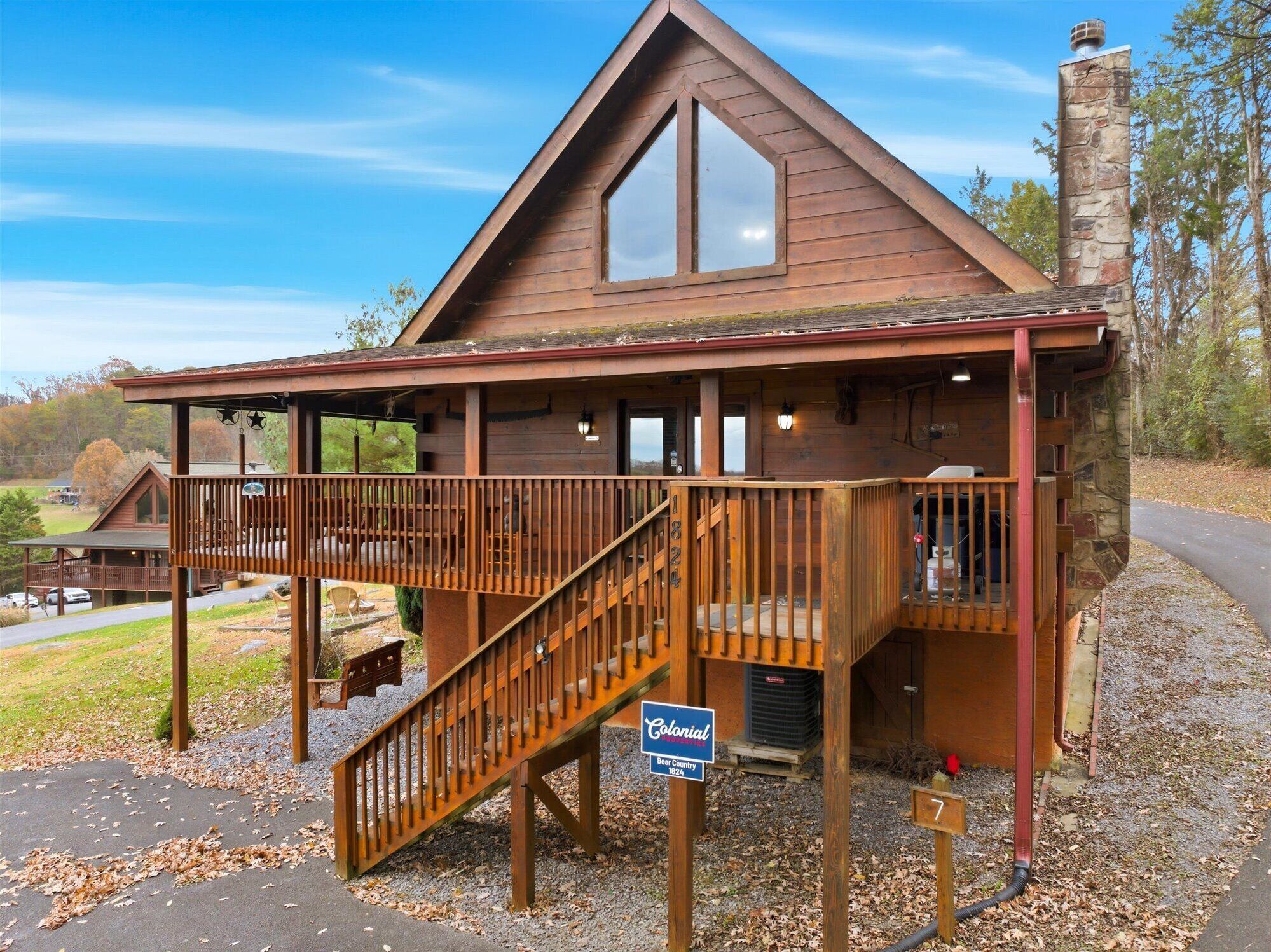 A wooden lodge with a balcony, a staircase, and a chimney.