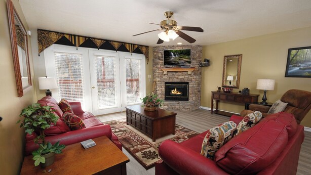 A living room with a fireplace, red leather sofas, a wooden coffee table, and a ceiling fan. - Dream Chaser: Minutes from Dollywood & Downtown (Pigeon Forge)