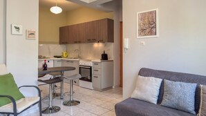 A compact living space with a kitchenette, a dining area with a table and chairs, and a sofa with cushions. - Alisahni Home 1 (Chania)