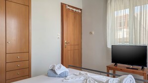 A hotel room with a bed, a TV, a wooden wardrobe, and a door. - Alisahni Home 1 (Chania)