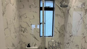 A bathroom with a toilet, bidet, and bathtub, all with marble flooring and walls. - Large 1 Bedroom Apartment - Chelsea (London)