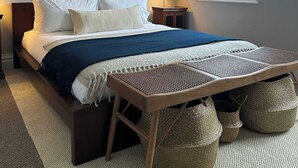 A neatly arranged bedroom with a large bed, a mirror, a bedside lamp, and a window with a view. - Large 1 Bedroom Apartment - Chelsea (London)