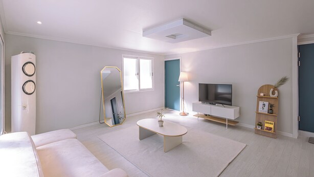 Una sala de estar moderna con un sofá blanco, una mesa de centro, un televisor y una estantería.
