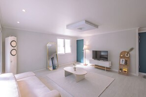 A modern living room with a white sofa, a coffee table, a TV, and a bookshelf. - moneystay inchon (Incheon)