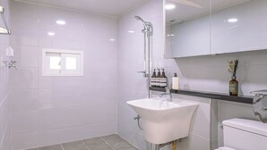 Un baño moderno con ducha, lavamanos, inodoro y un espejo grande.
