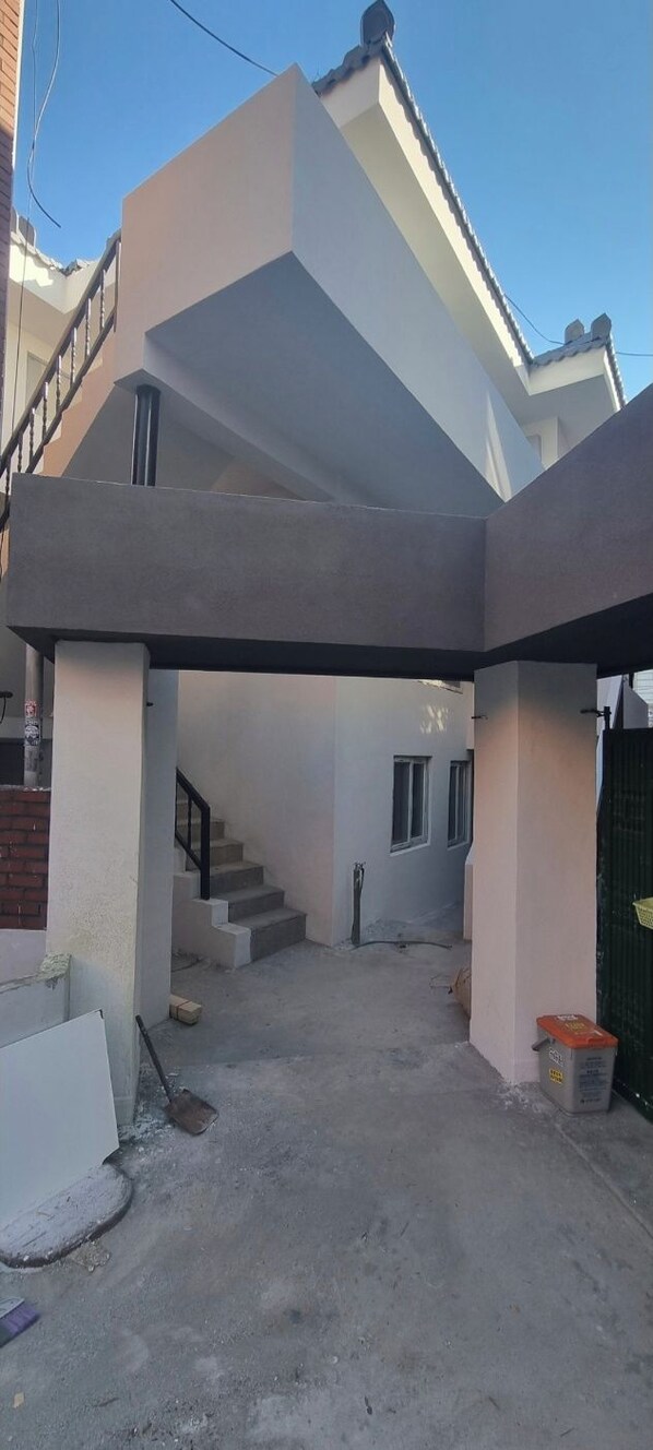 A modern two-story house with a covered patio area, a staircase, and a visible door leading to the interior. - moneystay inchon (Incheon)