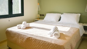 A neatly made bed with a quilted cover, two pillows, and rolled towels on a nightstand. - Casa Ankilena Corfu Garden Haven (Corfu)