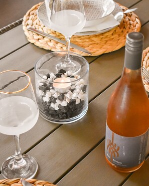 A table with a bottle of wine, two glasses, and a candle in a glass jar.