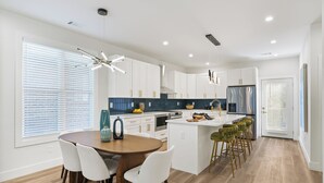 Een moderne keuken met witte kasten, een centraal eiland en barkrukken.