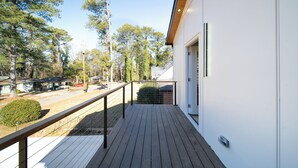 Een modern gebouw met een houten terras en een metalen hekwerk.
