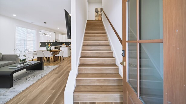 Een moderne woonkamer met een trap naar een eetgedeelte en keuken.