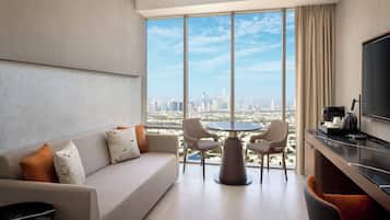 Ein modernes Hotelzimmer mit großem Fenster und Blick auf die Stadt, inklusive einer Couch, einem Esstisch mit Stühlen und einem Flachbildfernseher.