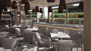 A modern restaurant with wicker furniture, hanging pendant lights, and a bar area with shelves of bottles and decorative items. - Hotel Local Dubai, Jumeirah Village Triangle, Autograph Collection (Dubai)
