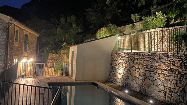 A swimming pool with stone walls and a stone building in the background. - Beautifully restored wine grower’s house with pool in stunning riverside village (Roquebrun)