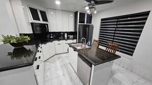 A modern kitchen with white cabinets, a black countertop, a built-in dishwasher, and a ceiling fan. - Luxury home with Pool, Electric Vehicle charger in McAllen near by hospitals and (McAllen)