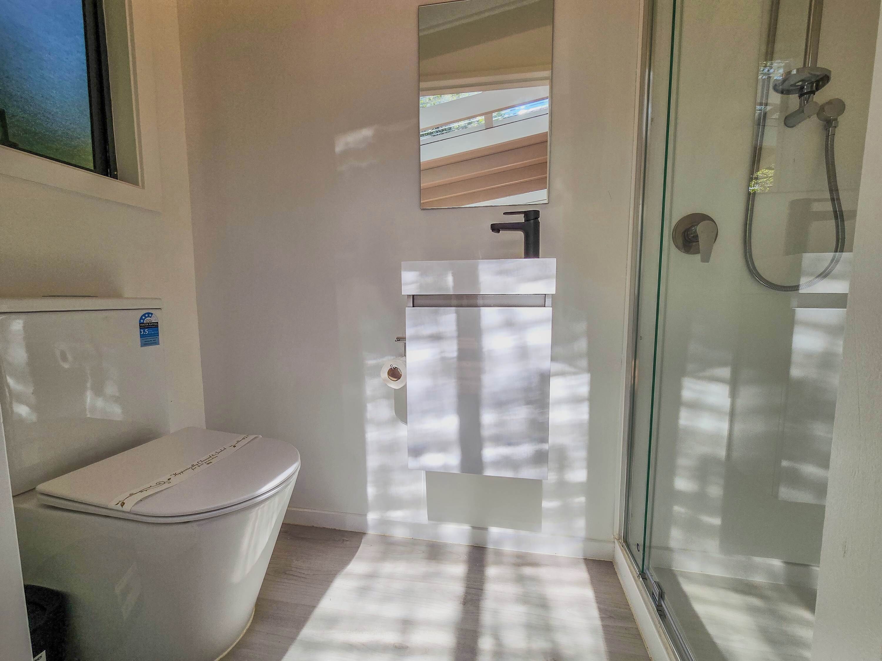 Et badeværelse med toilet, vask og brusebad.