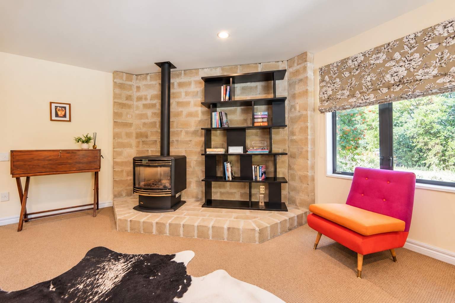A cozy living room with a fireplace, bookshelves, a sofa, and a rug.