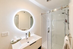 Een moderne badkamer met een ronde spiegel, een wastafel en een douchecabine met glazen wanden.