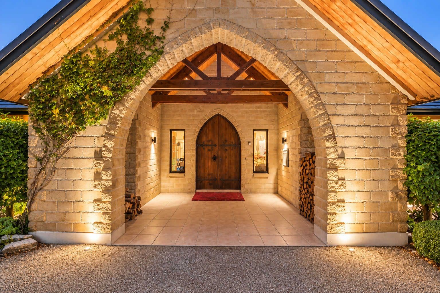 A stone building with a wooden door, a red carpet, and a brick wall with climbing plants.