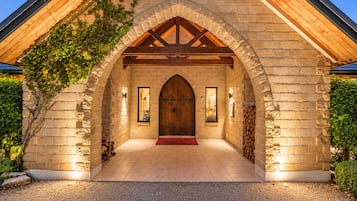 A stone building with a wooden door, a red carpet, and a brick wall with climbing plants.