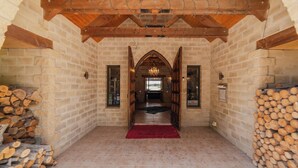A stone-walled room with a wooden ceiling, a chandelier, and a red carpet leading to a door. - 1BR Retreat Self-Contained & Private  - Waitaki (Lake Tekapo)