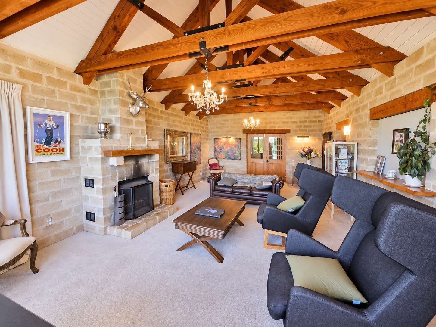 A spacious living room with a fireplace, a chandelier, and a cozy seating area.