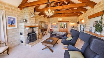 A spacious living room with a fireplace, a chandelier, and a cozy seating area.