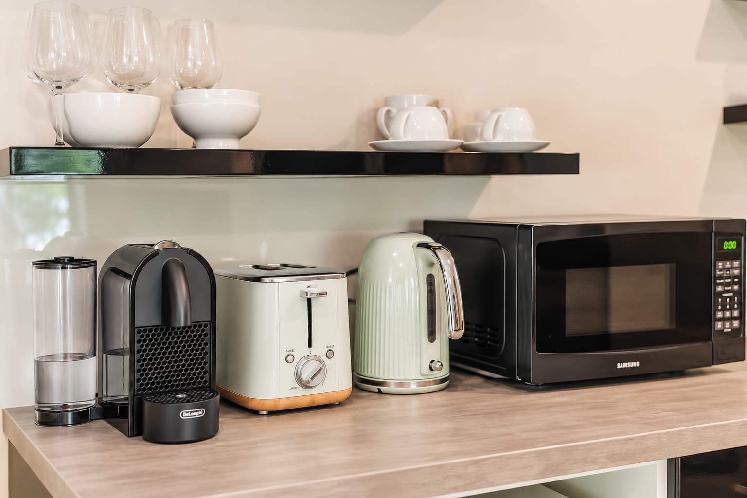 Un plan de travail de cuisine avec une machine à café, un grille-pain, une bouilloire et un four à micro-ondes.