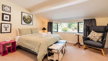 A bedroom with a bed, a chair, a small table, and a window with curtains.