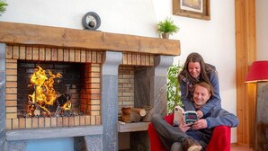 Ein Kamin mit Feuer, eine Uhr und eine Pflanze auf der Kaminbank.
