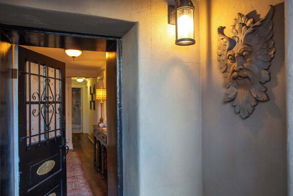 Un pasillo con un revestimiento decorativo y una puerta con ornamentación metálica detallada.