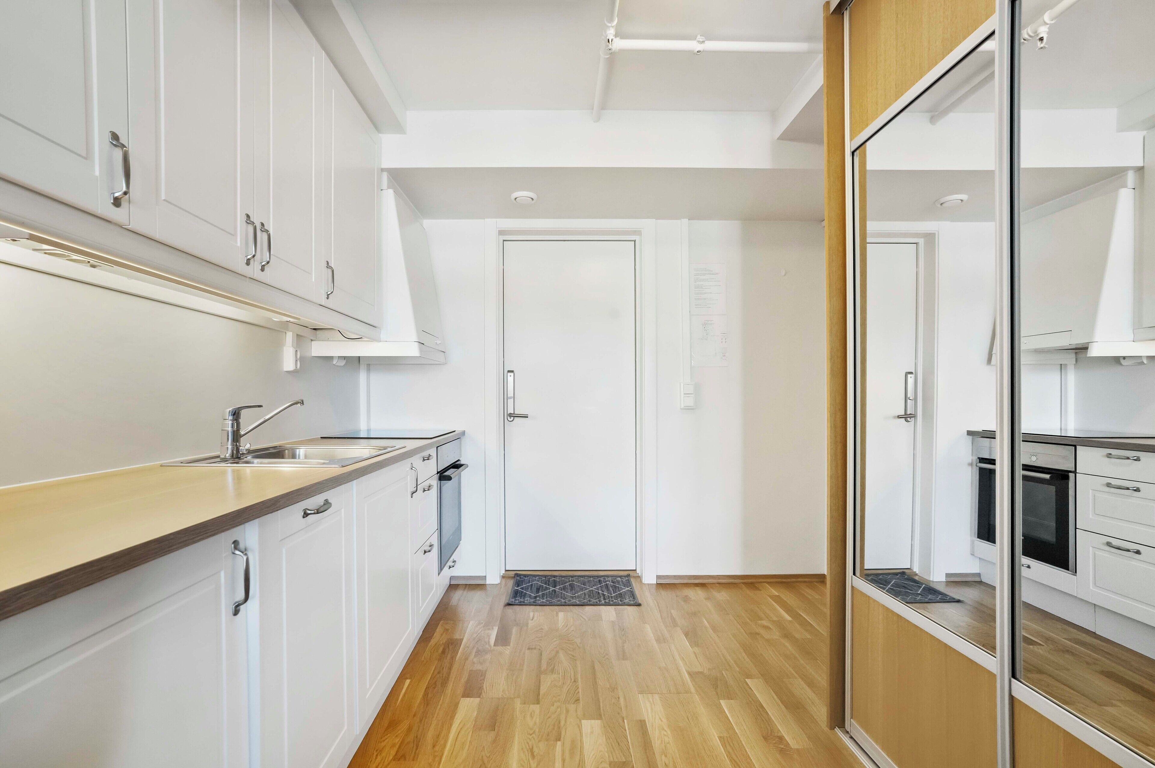 Una cocina moderna con armarios blancos, encimera de madera y horno empotrado.