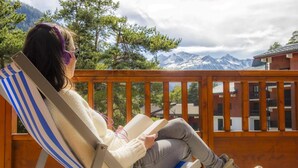 A person relaxing on a striped deck chair with a book, overlooking a mountainous landscape. - Ski-in/ski-out & foot of the slopes, swimming pool, balcony, tv, ski locker, 50m², La Norma (La Norma)