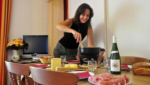 A dining table with a laptop, a bottle of wine, and a plate of food. - Ski-in/ski-out & foot of the slopes, swimming pool, balcony, tv, ski locker, 50m², La Norma (La Norma)