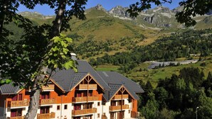 Un immeuble à plusieurs étages doté de balcons en bois, se dressant sur un fond de paysage montagneux.