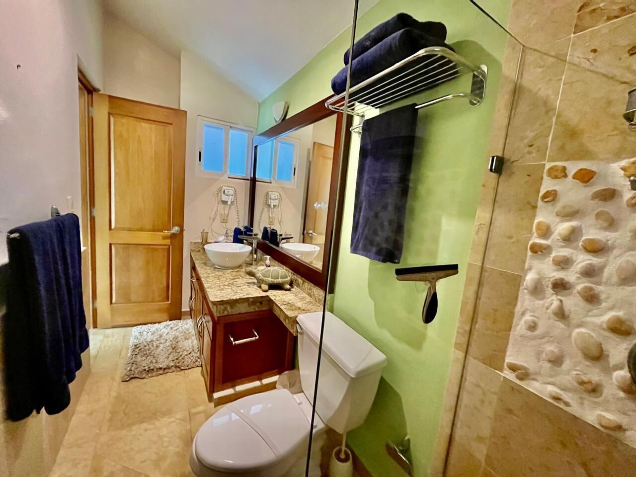 A bathroom with a shower, toilet, sink, and a towel rack.