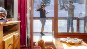A room with a large window, a television, and a table with a puzzle. - 200m from ski slopes, fitness, swimming pool, sauna, terrace, balcony, tv, ski locker, 35-40m² (Le Corbier)