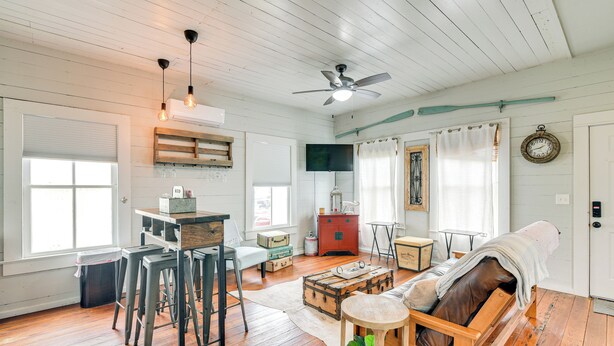 Un salon chaleureux avec un plancher en bois, un canapé, une table basse et un téléviseur fixé au mur.