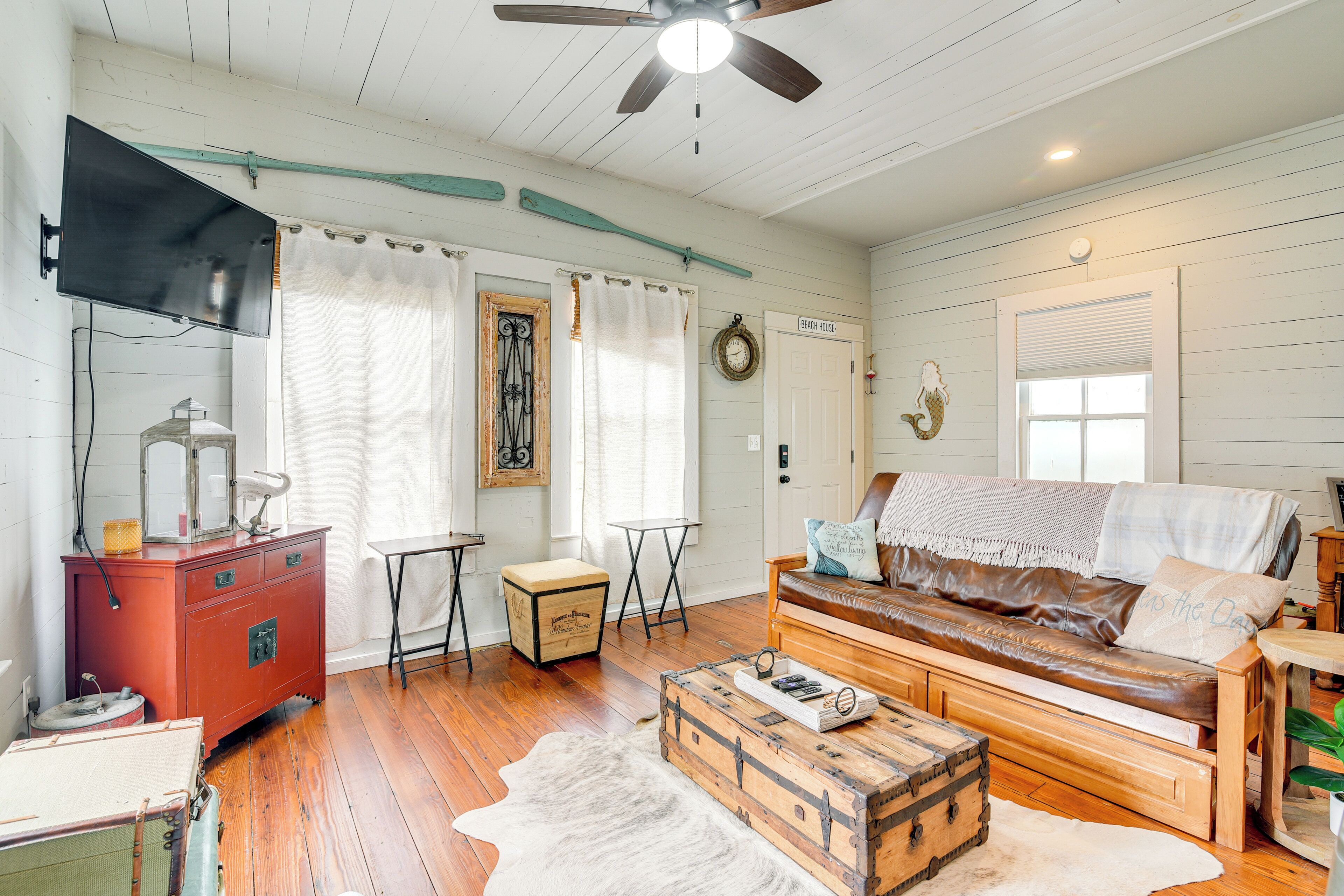A cozy living room with a wooden sofa, a red dresser, and a vintage suitcase.
