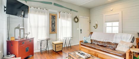 A cozy living room with a wooden sofa, a red dresser, and a vintage suitcase.