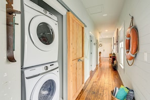 A laundry area with stacked washers and dryers, wooden doors, and a wooden floor.