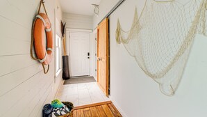 Un couloir avec un plancher en bois, une porte blanche au fond et un filet suspendu au mur.