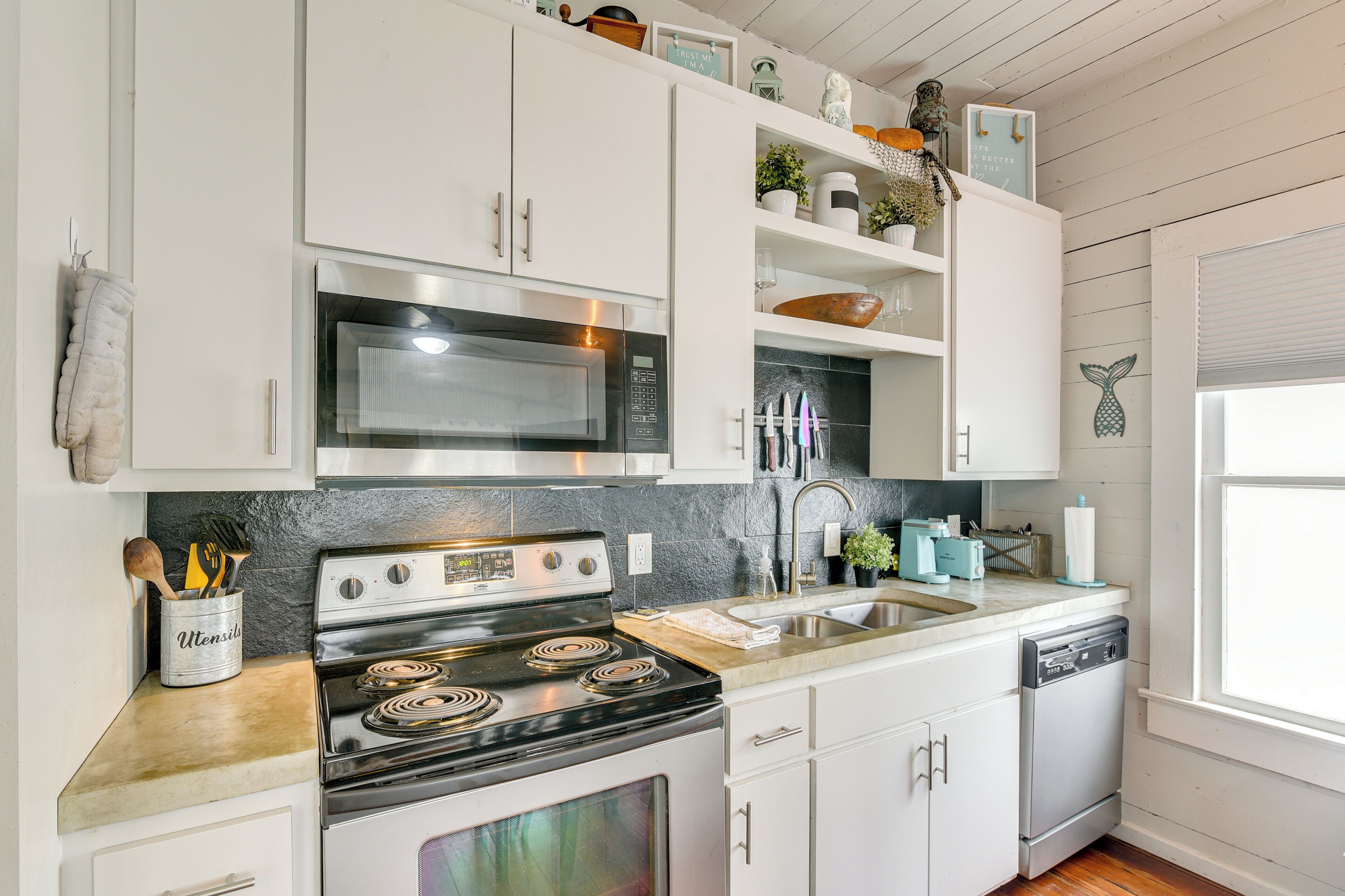 A modern kitchen with white cabinets, stainless steel appliances, and a granite countertop.